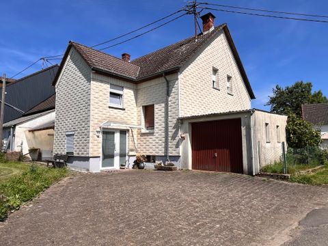 A large, bright house with a red garage door and garden. The building has a clean, modern style and is surrounded by green spaces.