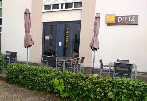 Ein Außenbereich eines Restaurants mit Tischen und Stühlen. Einige Sonnenschirme stehen auf der Terrasse.