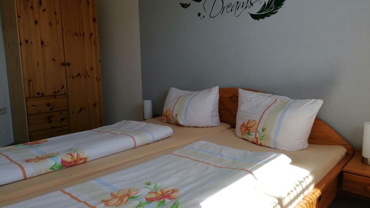 Ein gemütliches Schlafzimmer mit zwei Betten und einem Holzschrank. An der Wand steht der Schriftzug "Sweet Dreams".