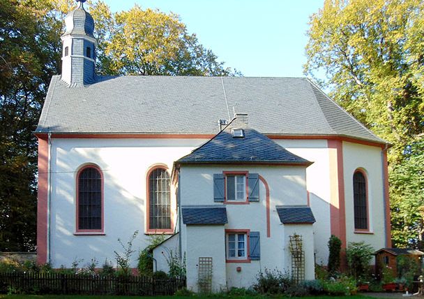 Schankweiler Klause, eine kleine Kapelle mit angrenzendem Gebäude, umgeben von Bäumen und einem Garten.