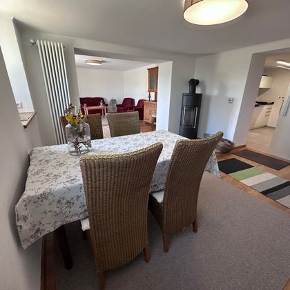 Ein gemütlicher Essbereich mit einem Tisch und vier Stühlen. Im Hintergrund ist ein offenes Wohn- und Küchenkonzept zu sehen.