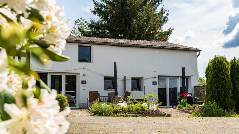 Ein charmantes Haus mit blühendem Garten und gemütlicher Terrasse. Die Umgebung ist grün und einladend.