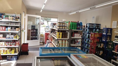A well-organized retail store with shelves full of food and drinks. Freezers are visible in the foreground.