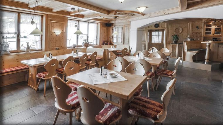 Un restaurant cosy avec un intérieur en bois et de nombreuses tables. Les fenêtres offrent une vue sur les environs, et la décoration est accueillante.