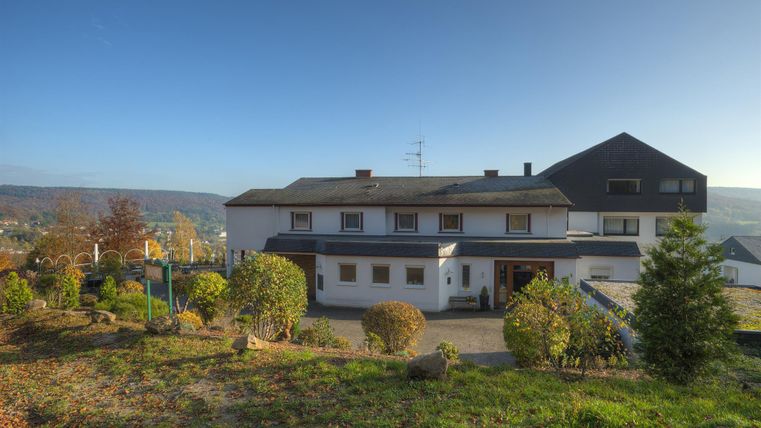 Ein modernes Gebäude umgeben von Grünflächen und kleinen Bäumen. Im Hintergrund ist eine klare, blaue Himmel zu sehen.