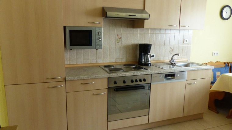 Une cuisine moderne avec des armoires en bois et des appareils en acier inoxydable. Elle comprend une cuisinière, un four, un micro-ondes et une cafetière.