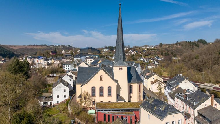 Eine malerische Stadt mit vielen Häusern und einer markanten Kirche. Der hohe Kirchturm ragt in den klaren blauen Himmel.