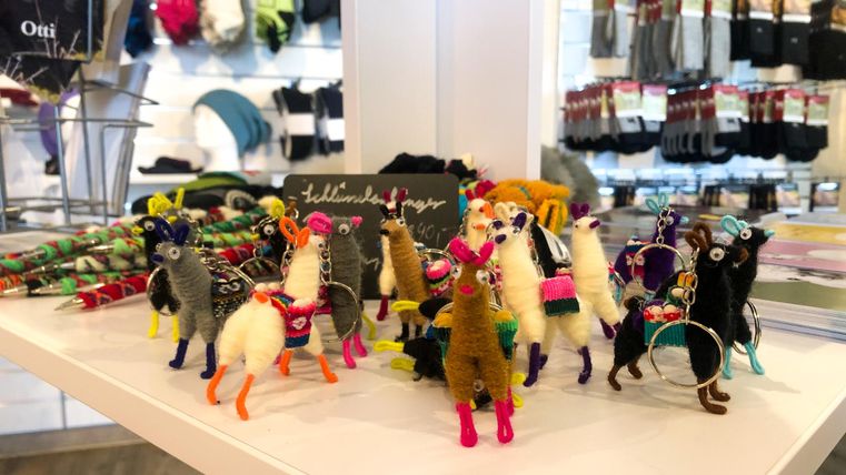 Un groupe de lamas colorés en laine faits main se tient sur une table. Ils sont conçus dans différentes couleurs et motifs.