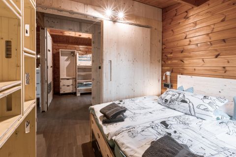 Ein modernes Schlafzimmer mit einem Doppelbett und Holzvertäfelung. Der Raum ist hell und gemütlich, mit einem offenen Zugang zu einem weiteren Bereich.