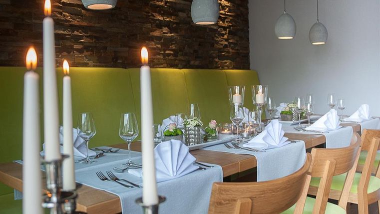 Ein elegantes Restaurant mit gedeckten Tischen und einer gemütlichen Atmosphäre. Kerzen und dekorative Details verleihen dem Raum einen besonderen Charme.
