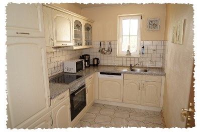 Une cuisine moderne avec des armoires claires et un plan de travail en marbre. Elle est bien équipée avec une cuisinière, un micro-ondes et un évier.