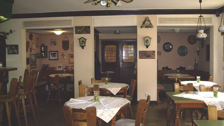 Ein gemütliches Restaurant mit Holzstühlen und Tischen. Die Wände sind mit Bildern und Dekorationen geschmückt.