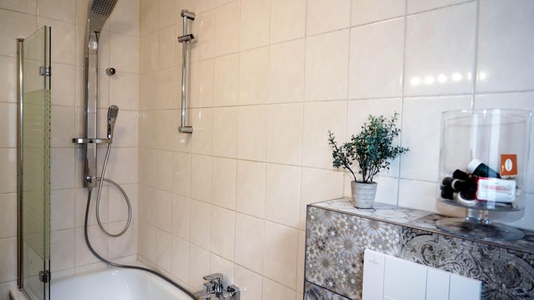 Een moderne badkamer met een badkuip inclusief waterval douche.