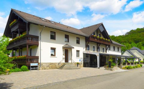 Ein hübsches Gebäude mit Balkonen, umgeben von Grün. Der Parkplatz vor dem Haus ist gut zugänglich.
