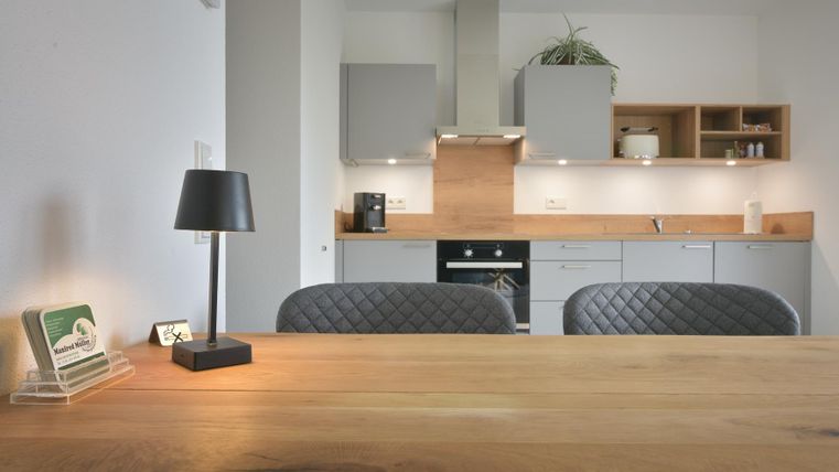 Een moderne keuken met houten oppervlakken en elegante meubels. Een tafel met decor en een lamp creëert een uitnodigende sfeer.