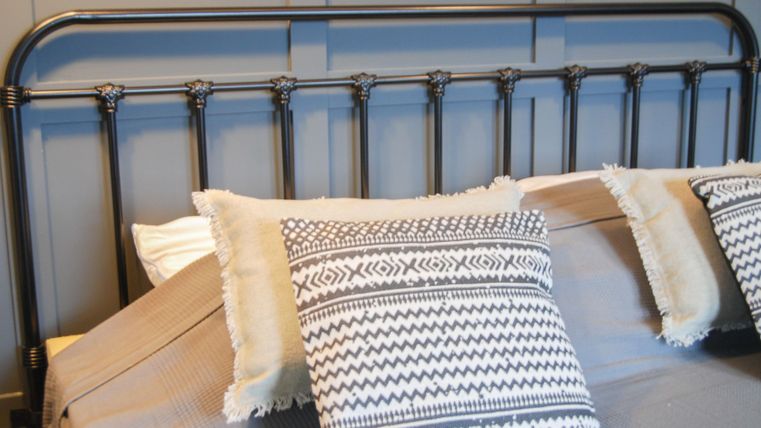 Ein schwarzmetallenes Bett mit Kissen in einem modernen Design. Die Bettwäsche ist schlicht und elegant, ideal für ein gemütliches Schlafzimmer.