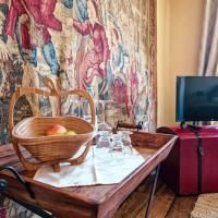 Een rustieke houten plank met een mand vol appels en glazen staat voor een wandtapijt. Op de achtergrond is een televisie te zien.