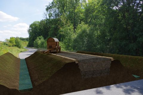 Eine historische Wagenansicht auf einem ungefährdenden Weg. Umgeben von grüner Landschaft und Bäumen.