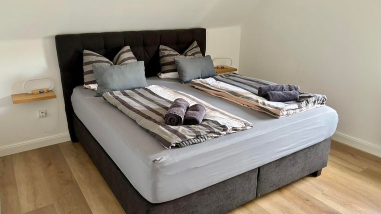 Ein modernes Schlafzimmer mit einem großen Doppelbett. Auf dem Bett liegen gestreifte Decken und Handtücher.