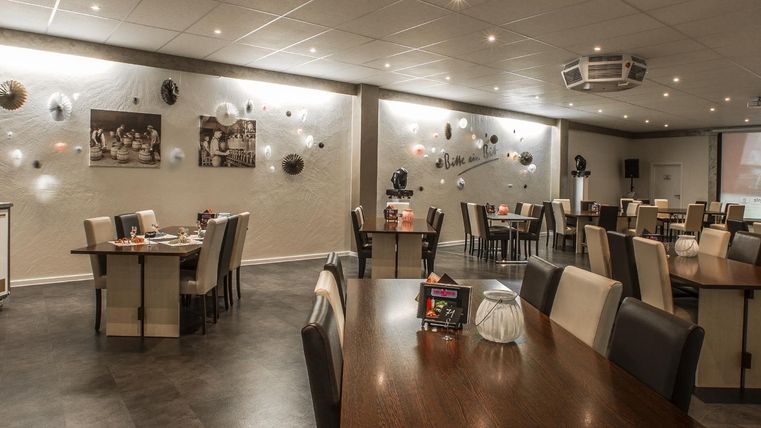 Ein modernes Restaurant mit hellen Tischen und Stühlen. Die Wände sind dekoriert und das Licht ist sanft.