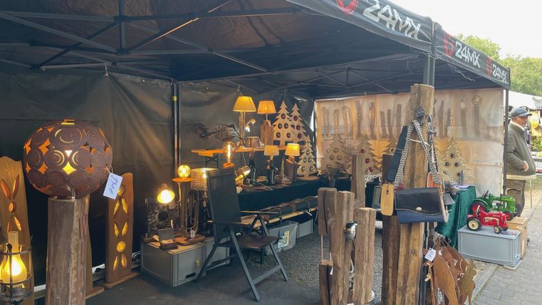 Ein markanter Marktstand mit handgefertigten Holzartikeln und dekorativen Lampen. Der Stand hat eine gemütliche Atmosphäre und bietet verschiedene kreative Produkte an.