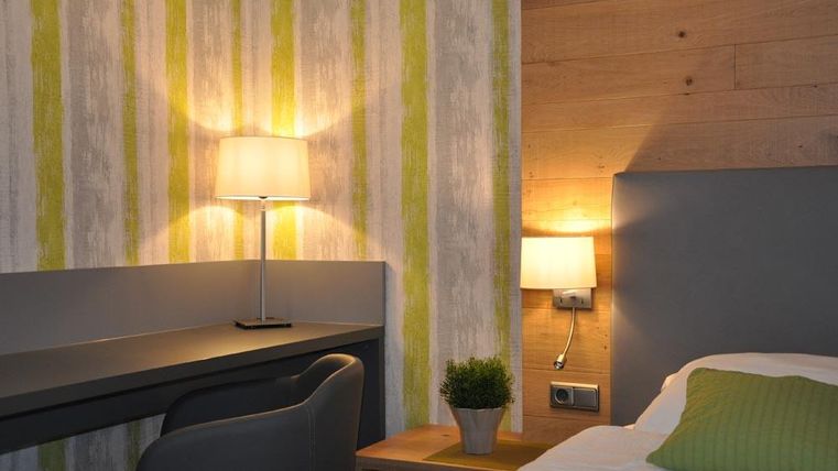 Une chambre moderne avec un mur en bois et des bandes d'accent vertes. La pièce est bien éclairée avec une atmosphère accueillante.