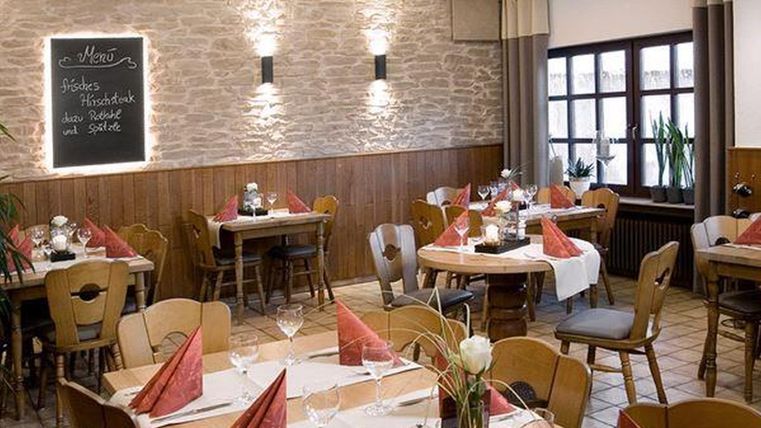 Un restaurant accueillant avec une ambiance rustique.
Les tables sont soigneusement dressées, et il y a un tableau avec le menu.