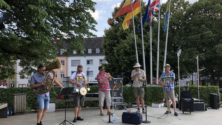 Eine Musikgruppe spielt im Freien. Im Hintergrund sind mehrere Flaggen zu sehen.