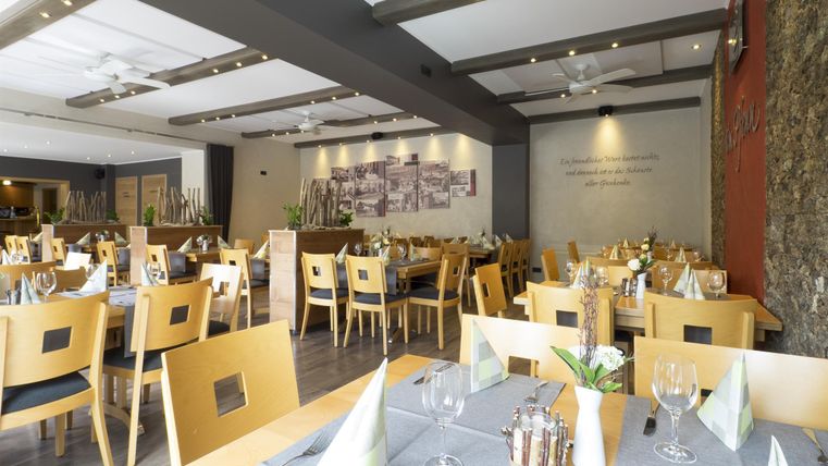 Ein modernes Restaurant mit Holztischen und Stühlen. Die Tische sind gedeckt und die Wände sind mit Fotos dekoriert.