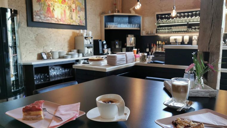 Een gezellige cafehoek met een moderne bar. Op de tafel staan koffie en cake, omringd door een warme sfeer.