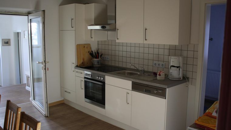 Eine moderne Küche mit hellen Schränken und einem Essbereich. Die Küchenzeile ist gut ausgestattet mit Herd, Backofen und Spüle.