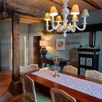 Een gezellige eetruimte met een grote houten tafel en elegante stoelen. Een decoratieve plafondlamp en een stijlvolle kast geven de ruimte charme.