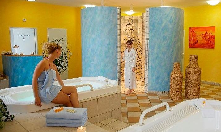 Een ontspannende spa met whirlpools en zachte verlichting. Een vrouw zit in een badjas en geniet van de rustige sfeer.