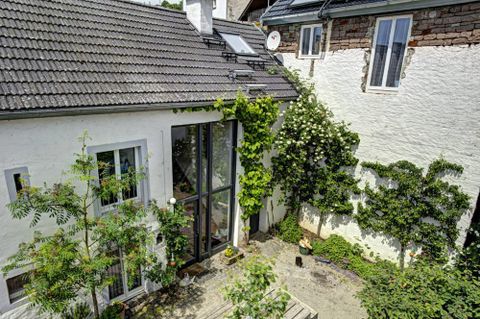 Een licht, modern huis met grote ramen en een groen binnenplaats. Omringd door planten en bomen straalt de tuin een rustige sfeer uit.