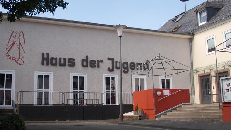 Ein Gebäude mit der Aufschrift "Haus der Jugend". Es hat große Fenster und eine zugängliche Treppe.