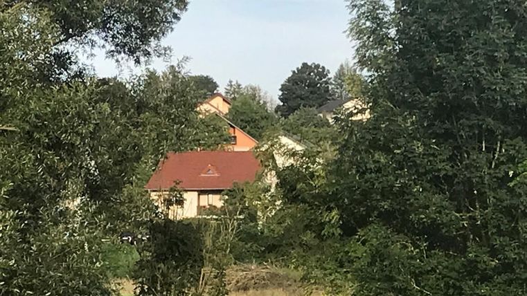 Un aperçu d'un bâtiment résidentiel tranquille, entouré d'arbres et de verdure. Le ciel est légèrement nuageux.