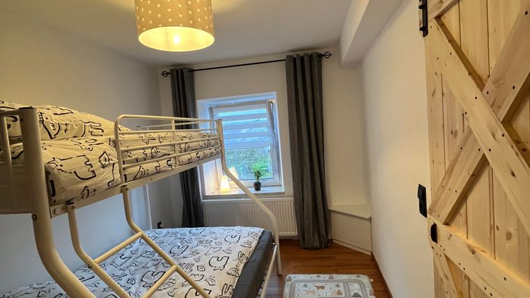 Une chambre confortable avec un lit superposé et une fenêtre. La pièce a un look moderne avec un détail en bois et un éclairage chaleureux.