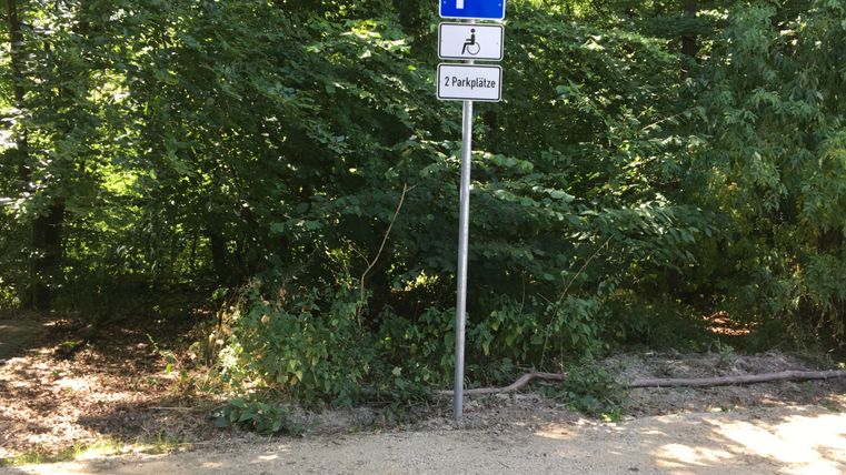 Parkplatzschild für Behinderte im Wald mit zwei Parkplätzen.