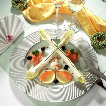 Een elegant opgemaakt bord met zeevruchten, gerookte zalm en schijfjes citroen. Daarbij een glas wijn en decoratieve servetten.
