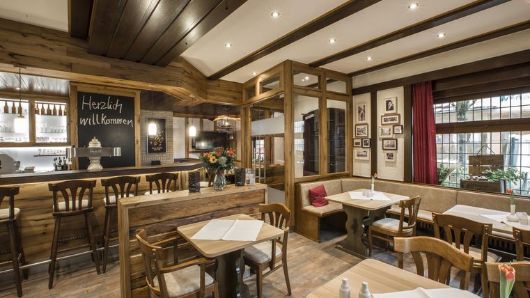 Ein gemütliches Restaurant mit Holzverkleidung und warmem Licht. Die Tische sind ordentlich gedeckt und die Atmosphäre ist einladend.