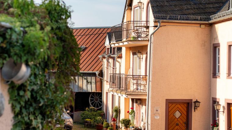 Eine ruhige Straße mit charmanten Häusern. Grüne Pflanzen und ein klarer Himmel schaffen eine einladende Atmosphäre.