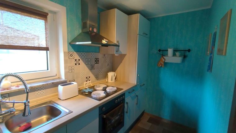 Eine moderne Küche mit blauen Wänden und hellen Möbeln. Sie ist gut ausgestattet und bietet einen gemütlichen Raum zum Kochen.