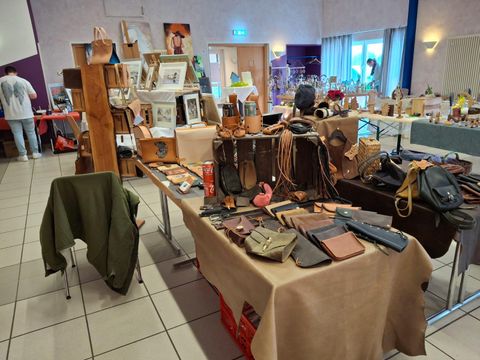 Ein Marktplatz mit verschiedenen Handwerksprodukten, darunter Taschen und Schmuck. Viele Tische sind mit kleinen Kunstwerken und Dekorationsartikeln dekoriert.
