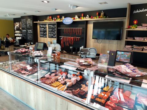 Een slagerij met een groot assortiment aan worst en vlees in vitrines. Op de achtergrond zijn verdere producten en de verkoopruimte te zien.