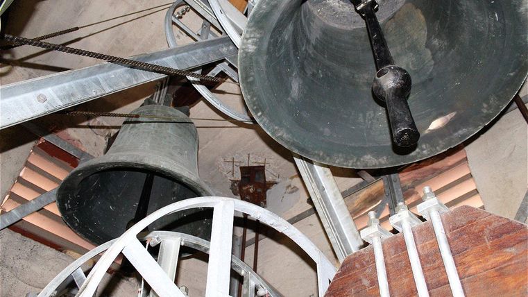 Une vue des cloches dans une tour. La structure montre des pièces mécaniques et les cloches sont visibles.