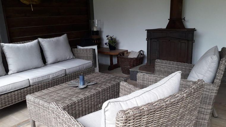 Ein stilvoller Sitzbereich mit einem Sofa und Stühlen aus Rattan. Der Raum hat eine gemütliche Atmosphäre mit einem Kamin und einfachen Dekorationen.