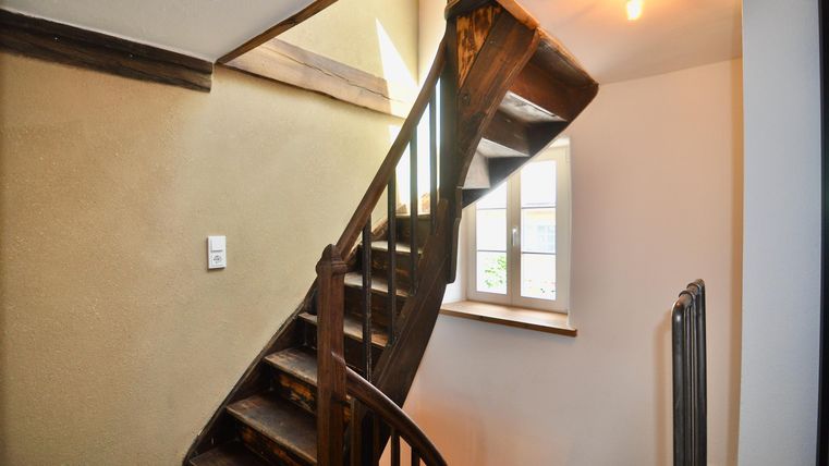 Eine hübsche Wendeltreppe aus Holz in einem hellen Raum. Das Fenster sorgt für viel Tageslicht.