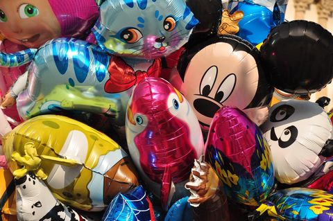 Bunte, aufgeblasene Ballons in verschiedenen Formen und Figuren sind übereinander gestapelt. Sie zeigen bekannte Charaktere und Tiere, die Freude und Feierlichkeit ausstrahlen.