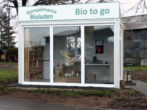 Een kleine biologische winkel met grote vensterfronten. De winkel biedt verse, biologische producten om mee te nemen aan.