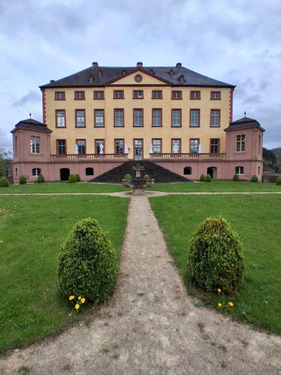 Un grand château avec un jardin élégant. Le chemin mène à l'avant du bâtiment, qui est entouré de douces pelouses.